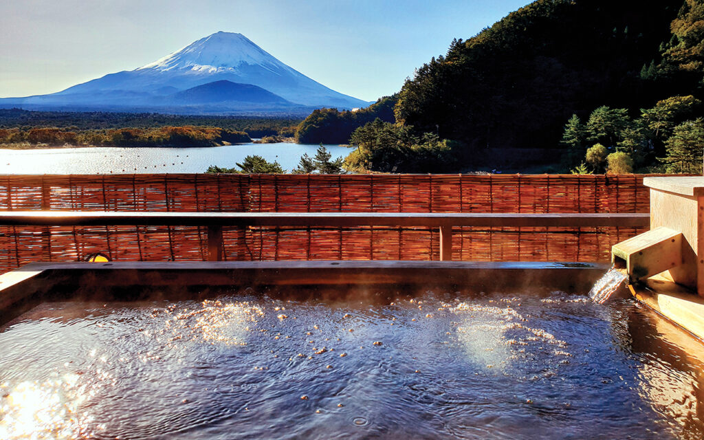 The Exotic beautiful peaceful scene of Onsen, japanese hot tub in the morning. background is Fuji Mountain.